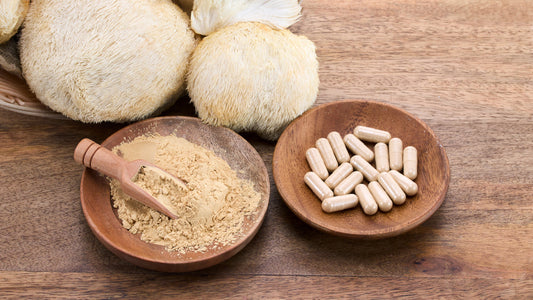 Best Lion’s Mane Supplement. Lion’s mane mushrooms, mushroom powder and capsules are on a wood table in wood bowls.