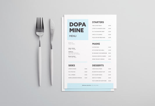 Printed out paper dopamine menu on a grey background next to a knife and fork.