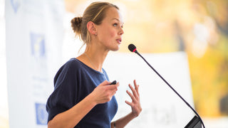 Woman speaking confidently at a microphone. Best Supplements for Performance Anxiety