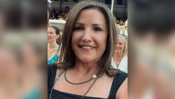A dark haired woman in a black dress. This is Patricia who uses Mind Lab Pro to help with brain fog.