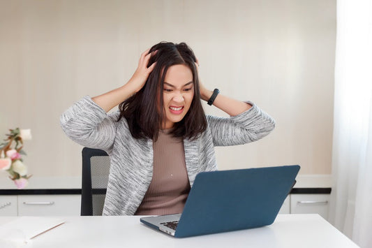 Best Nootropic Supplements for Anger and Irritability. An irritated woman clutches her head and scowls at her laptop.