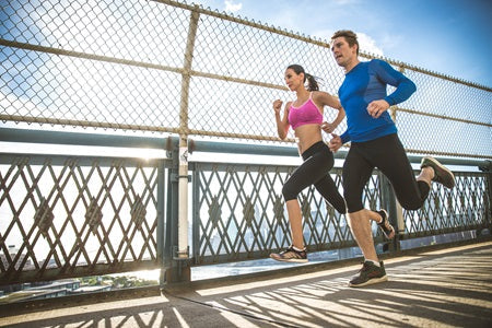 Best Supplements for Runners in 2025. Energetic man and woman running over a bridge.