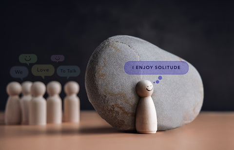 Best Nootropic Supplements for Introverts in 2025. A small wood person sculpture stands alone next to a rock, happy being alone.