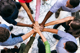 How Can Diversity Make Us Smarter with a group of people joining hands in a huddle